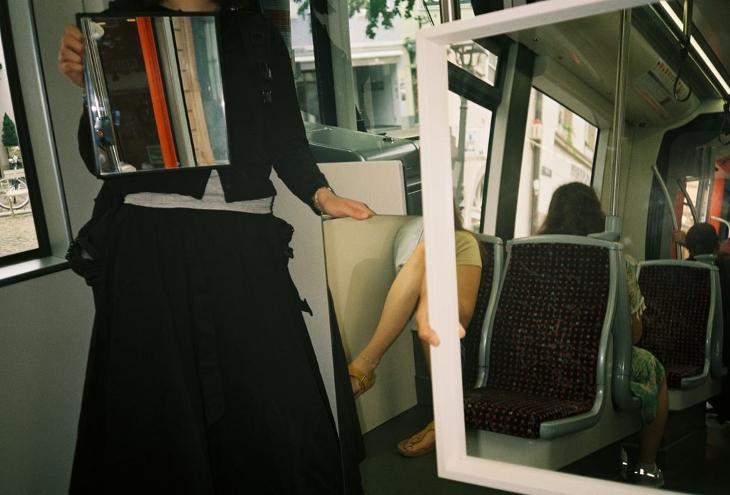 Two mirrors inside a tram reflecting rows of seats, windows, and passengers in overlapping layers.