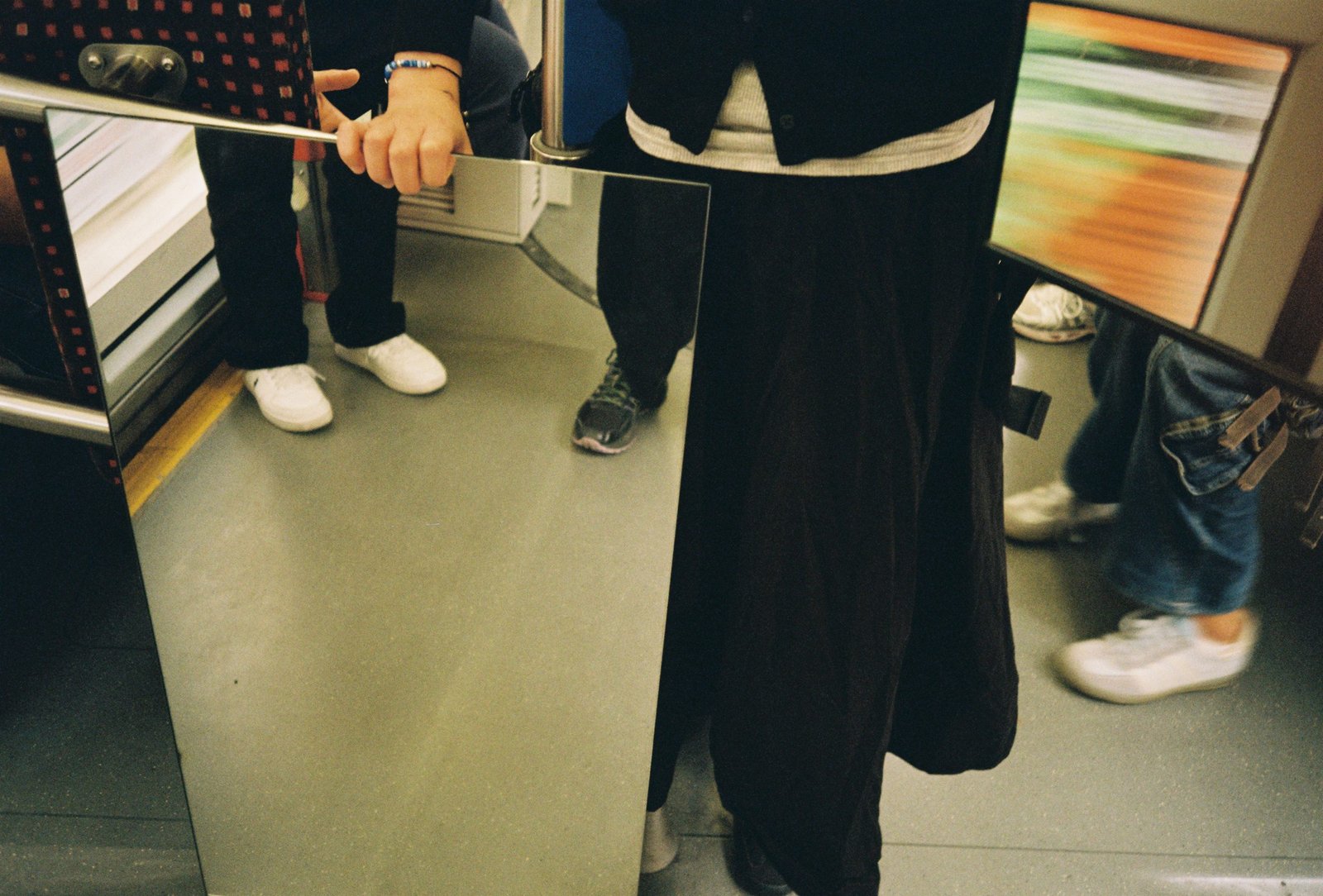 Several mirrors inside a tram reflecting fragmented views of legs, feet, and the floor.