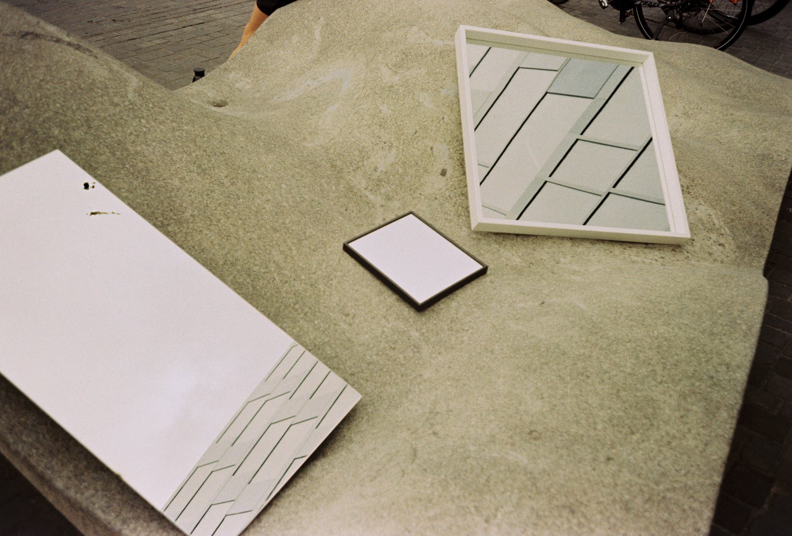 Several mirrors of different sizes placed on a concrete surface in Freiburg, reflecting the surrounding architecture.