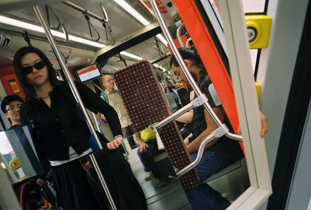 Mirror inside a tram fragmenting and recomposing seats, handrails, and passengers.